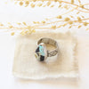 The black jack turquoise ring styled on tan linen with dried grass