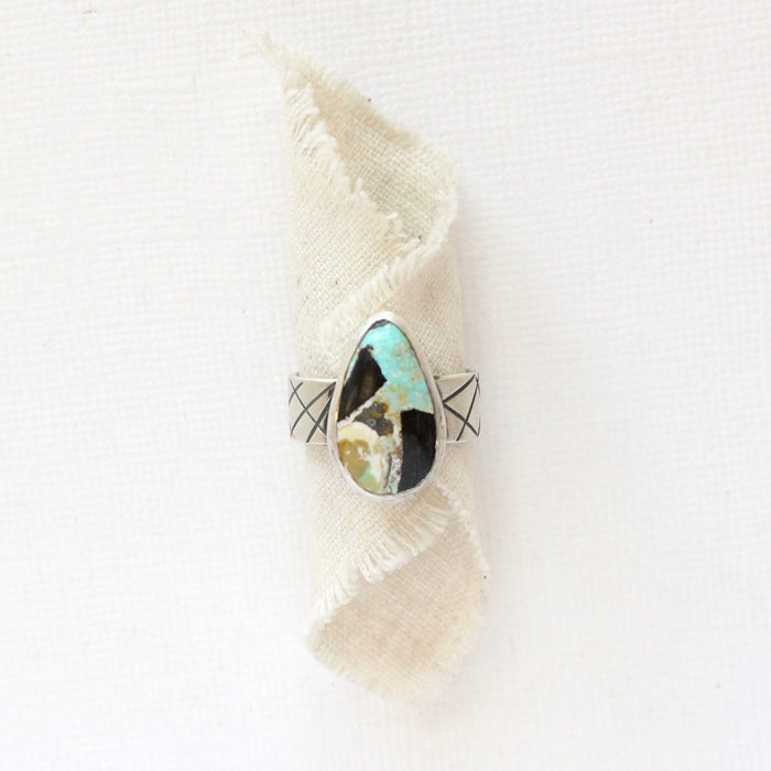 The black jack turquoise band ring styled on rolled tan linen