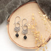 The black tourmaline jolie earrings styled on wood with gray velvet and dried grass