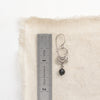 A black tourmaline jolie earring next to a ruler for size reference