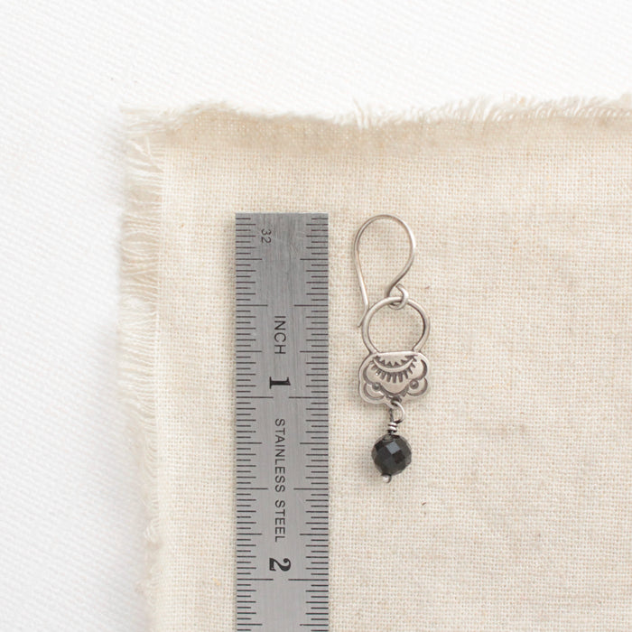 A black tourmaline jolie earring next to a ruler for size reference