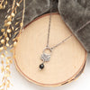 The black tourmaline jolie necklace styled on wood with gray velvet and dried grass