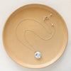 The blue bloom vintage plate necklace styled on a tan plate to show the adjustable lobster clasp closure