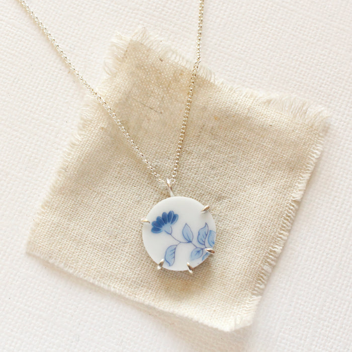 The blue bloom vintage plate necklace styled on tan linen