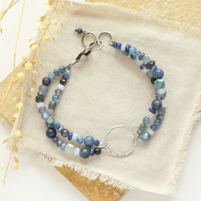 The blue double strand bracelet styled on a tan rock with linen and dried grass