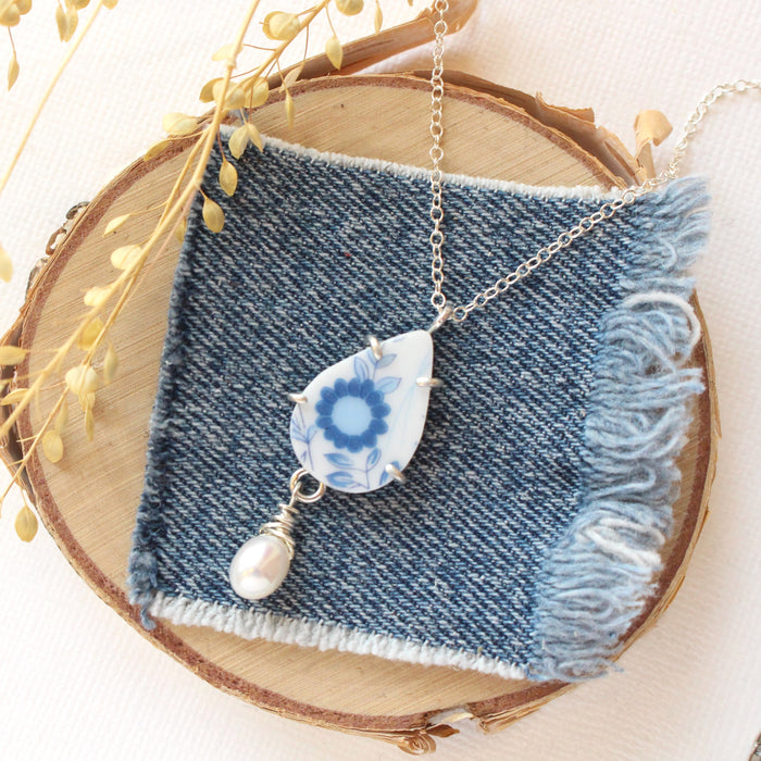 The blue flower and pearl drop vintage plate necklace styled on wood with linen and dried grass