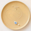 The blue flower and pearl drop vintage plate necklace styled on a tan plate to show the adjustable lobster clasp closure