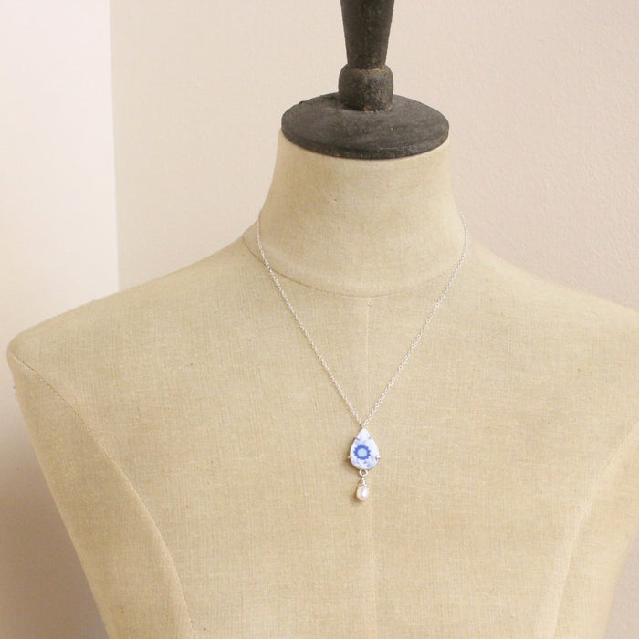 A mannequin wearing the blue flower and pearl drop vintage plate necklace