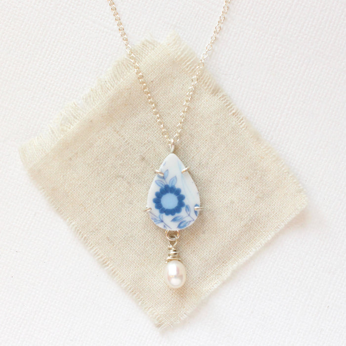 The blue flower pearl drop necklace styled on tan linen