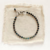 The blue tourmaline and brass bracelet styled on tan linen