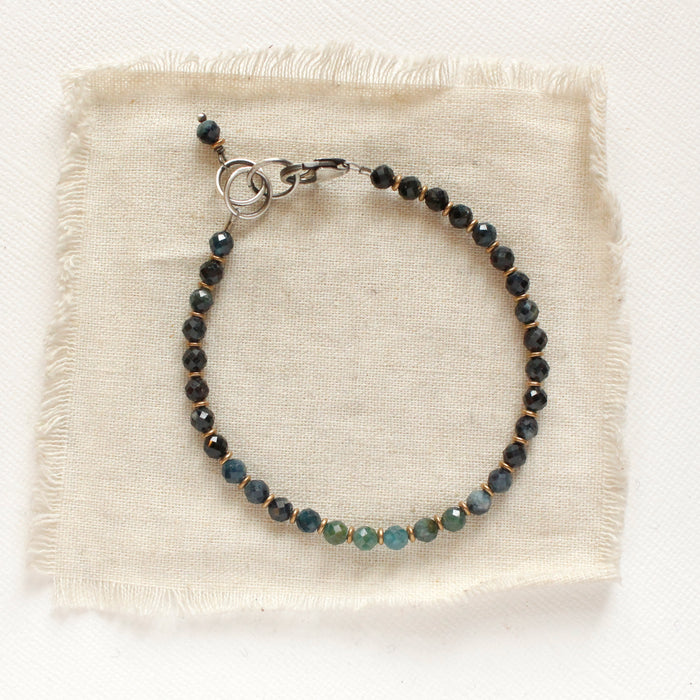 The blue tourmaline and brass bracelet styled on tan linen
