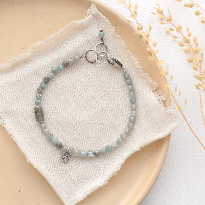 The zircon and labradorite roma bracelet styled on a tan plate with linen and dried grass