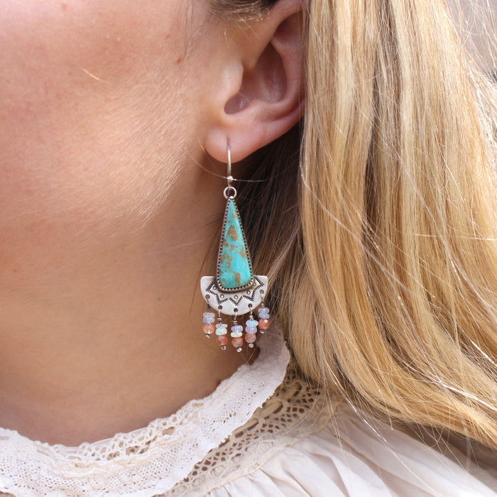 The boho turquoise triangle fringe earrings being worn