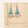 The boho turquoise triangle fringe earrings on a wooden ruler for size reference