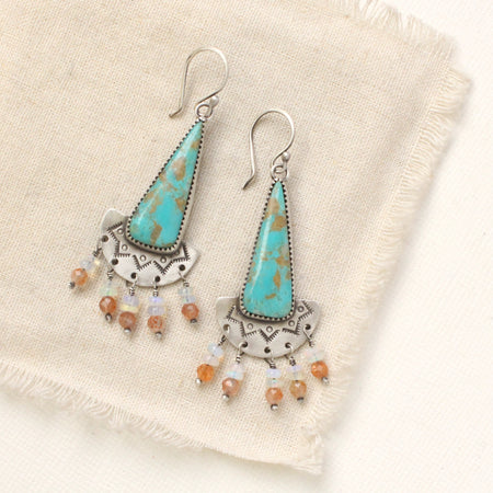 The boho turquoise, sunstone, and opal fringe earrings styled on tan linen