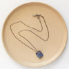 The pinned boulder opal necklace styled on a tan plate to show the adjustable lobster clasp closure