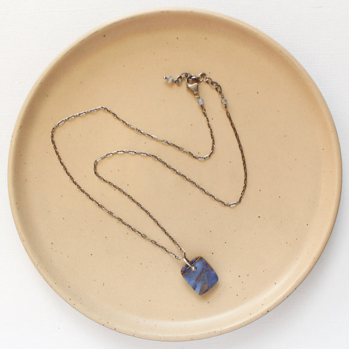 The pinned boulder opal necklace styled on a tan plate to show the adjustable lobster clasp closure