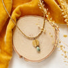 The brass and african jasper drop necklace styled on wood with yellow velvet and dried grass