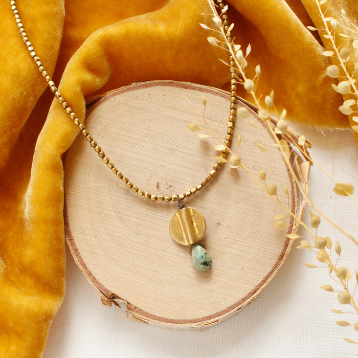 The brass and african jasper drop necklace styled on wood with yellow velvet and dried grass