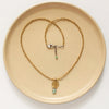 The brass and african jasper drop necklace styled on a tan plate to show the adjustable lobster clasp closure