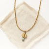 The brass and african jasper drop necklace styled on tan linen