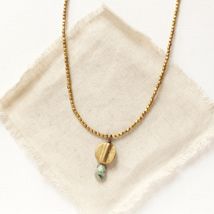 The brass and african jasper drop necklace styled on tan linen