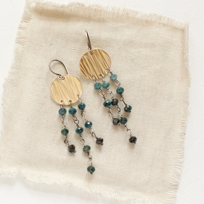 The grandidierite mythos chandelier earrings styled on tan linen
