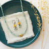 The brass and kyanite dangle earrings styled on a blue plate with the matching necklace