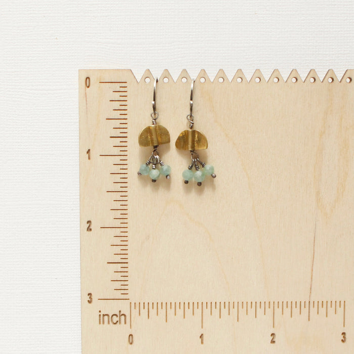 The brass and kyanite dangle earrings on a wooden ruler for size reference