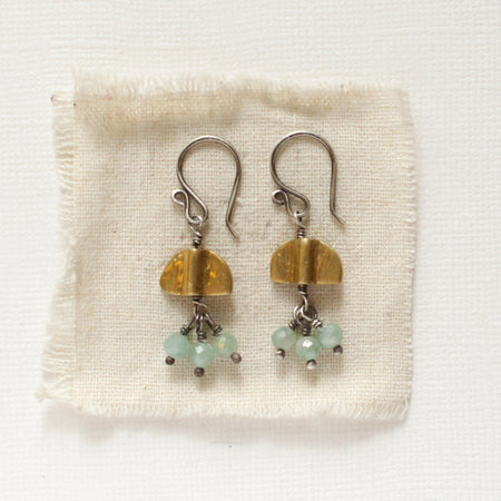 The brass and kyanite dangle mythos earrings styled on tan linen