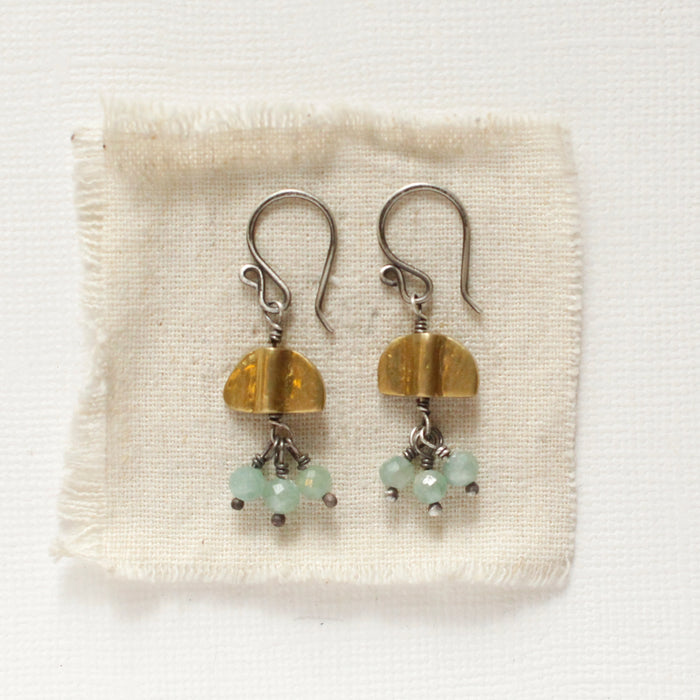The brass and kyanite dangle mythos earrings styled on tan linen