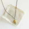 The brass and kyanite mythos necklace styled on tan linen