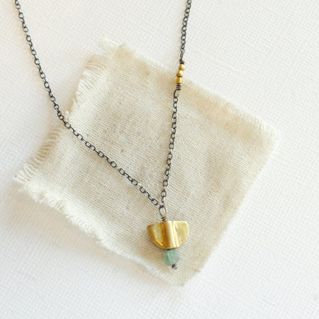 The brass and kyanite mythos necklace styled on tan linen
