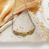 The brass trio mythos necklace styled on a white rock with orange velvet and dried grass