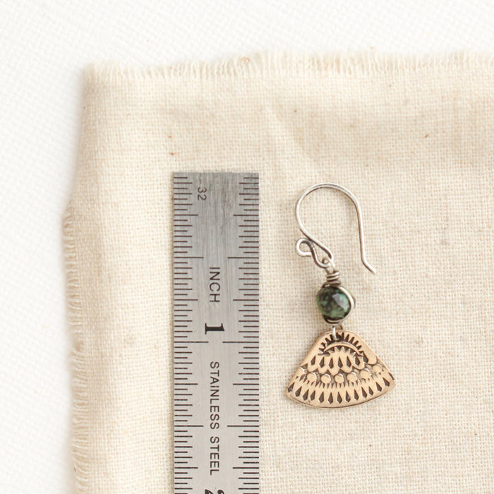 A bronze asmi triangle african jasper earring next to a ruler for size reference