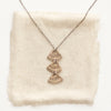 The bronze asmi trio triangle necklace styled on tan linen