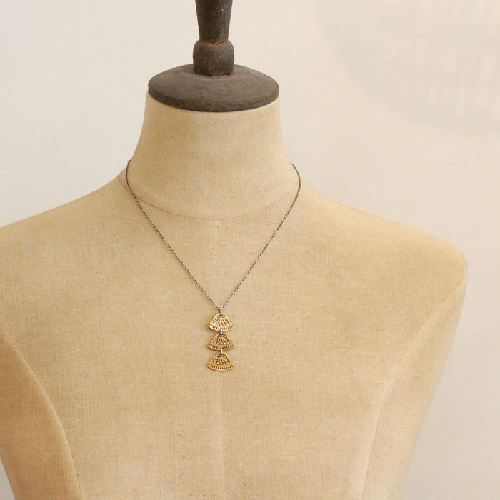 A mannequin wearing the bronze asmi trio triangle necklace