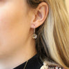 The bronze mini cactus flower lobe hugger earrings being worn in an ear