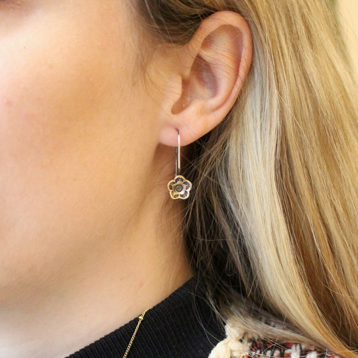 The bronze mini cactus flower lobe hugger earrings being worn in an ear