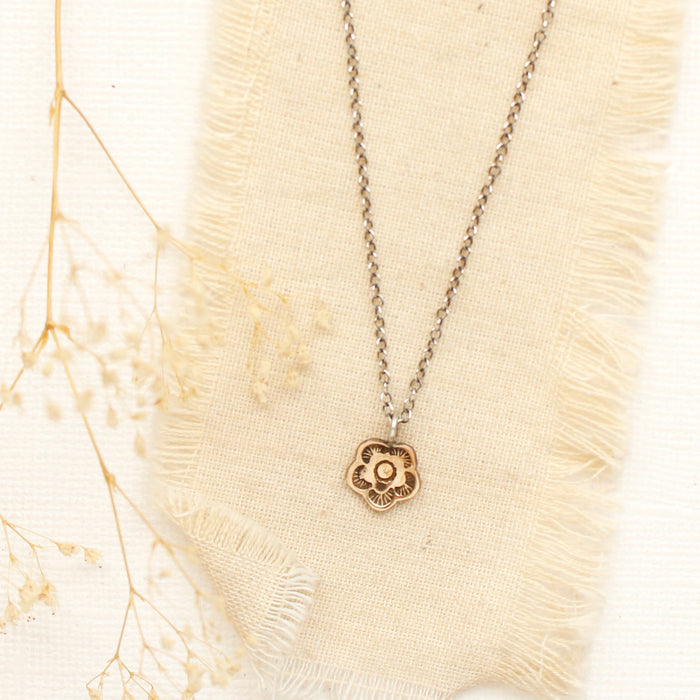 The bronze mini cactus flower necklace styled on linen with dried grass