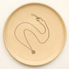 The bronze mini cactus flower necklace styled on a tan plate to show the adjustable lobster clasp closure
