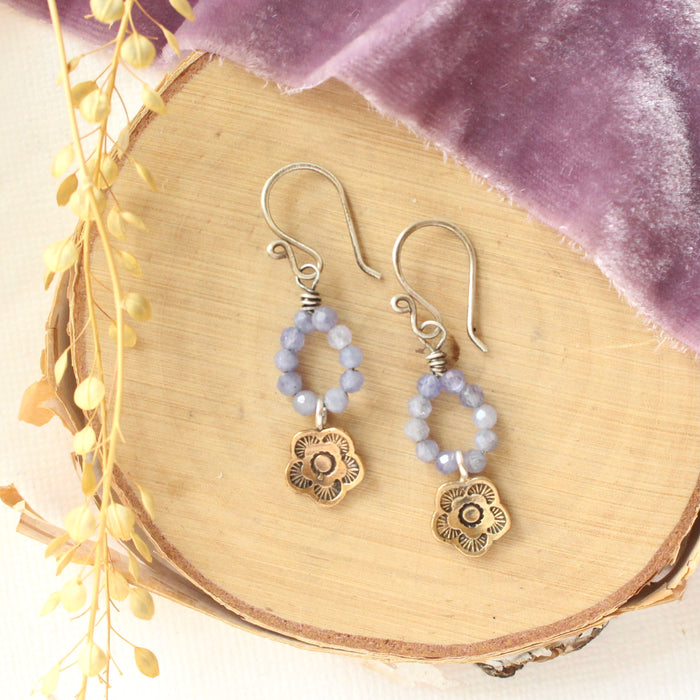The bronze mini cactus flower tanzanite hoop earrings styled on wood with purple velvet and dried grass