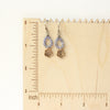 The bronze mini cactus flower tanzanite hoop earrings on a wooden ruler for size reference