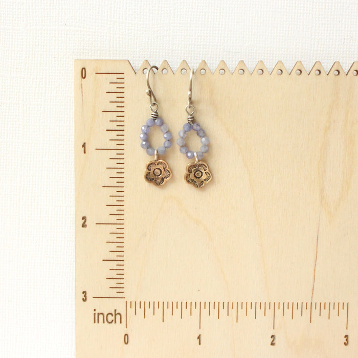 The bronze mini cactus flower tanzanite hoop earrings on a wooden ruler for size reference