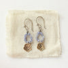 The bronze mini cactus flower tanzanite hoop earrings styled on tan linen