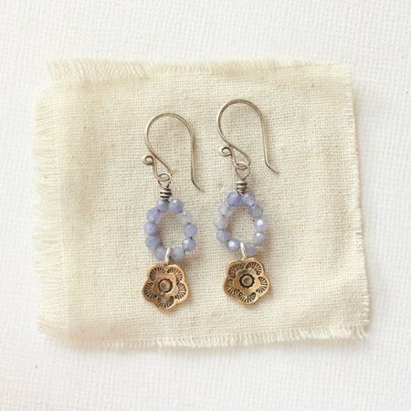 The bronze mini cactus flower tanzanite hoop earrings styled on tan linen