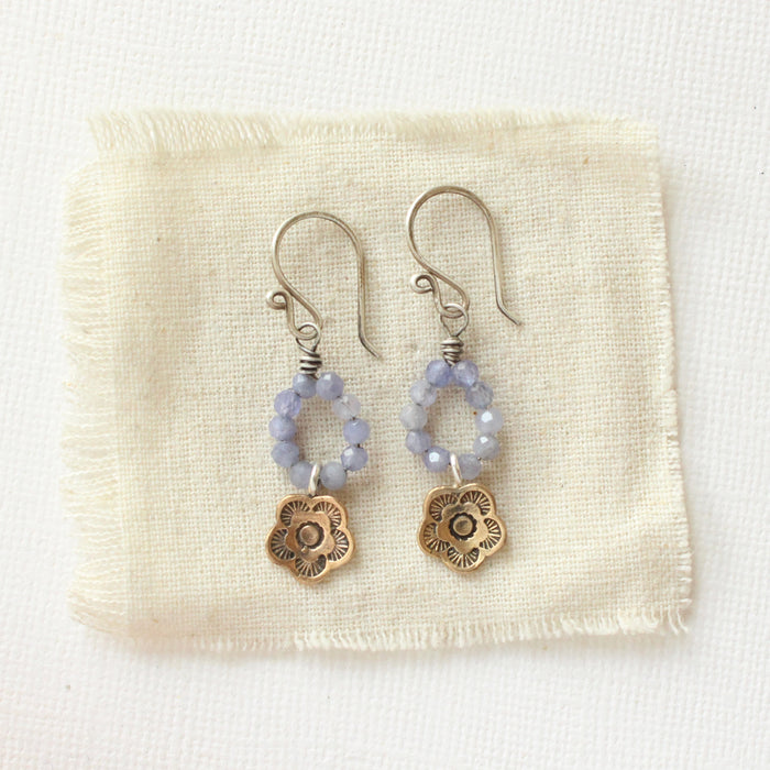 The bronze mini cactus flower tanzanite hoop earrings styled on tan linen