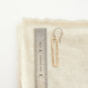 A bronze open bar earring next to a ruler for size reference