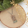 The bronze wanderer arch green apatite necklace styled on wood with green velvet and dried grass