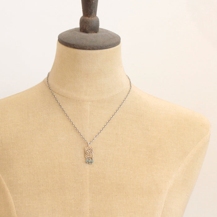 A mannequin wearing the bronze wanderer arch green apatite necklace 